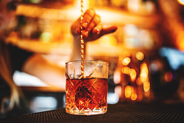 woman bartender hand making negroni cocktail. Negroni classic cocktail and gin short drink with sweet vermouth, red bitter liqueur