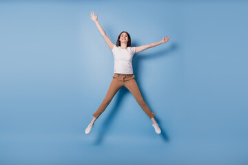 Portrait of dreamy inspired crazy lady jump enjoy weekend time raise hands on blue background