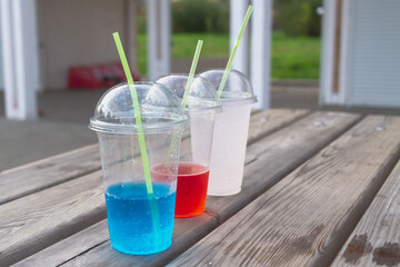 Transparent plastic glasses with soda in three colors red blue white
