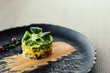 Colorful avocado tartar on a black plate at a restaurant