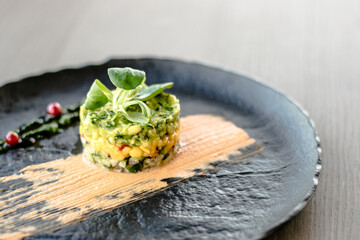 Colorful avocado tartar on a black plate at a restaurant