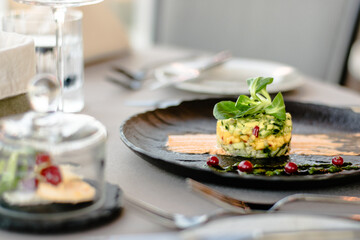 Colorful avocado tartar on a black plate at a restaurant