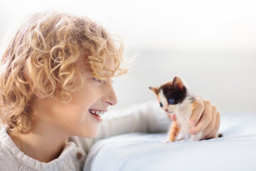 Child playing with kitten. Cat and kid at home.