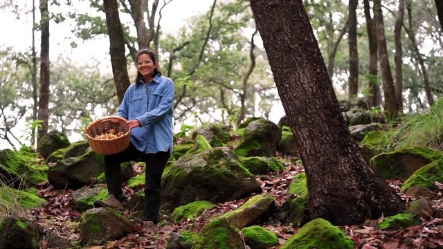 Woman attentively looking at camera with mushroom in woods