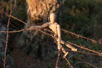 Wooden man and barbed wire, danger or unfreedom concept.