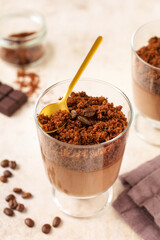 Delicious dessert chocolate mousse with brownie in glass jars on a light slate, stone or concrete background. Selective focus