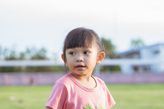 Portrait​ image of​ 3-4 years old​ baby​ child. Face of smiling​ Asian​ girl in head shot. Happy​ kid playing​ at the park playground. In summer or spring​ season.
