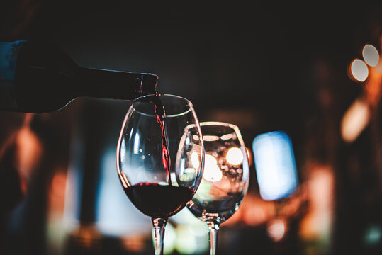 waiter pouring red wine into a glass in cafe or bar