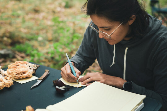 Woman writing names of mushrooms on paper