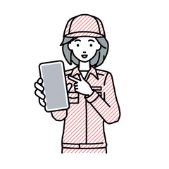立ってスマートフォンを指差してこちらに向けて見せている作業員の女性