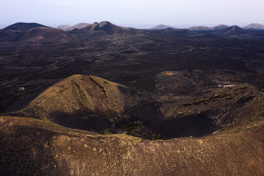 Crater of volcano with vines against rough mountains