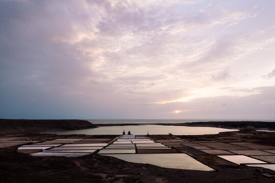 Salt flats against lagoon and ocean in sunlight