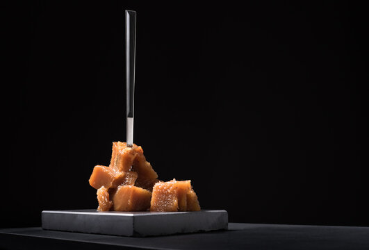 Gourmet quince jelly paste in ceramic plate on black background
