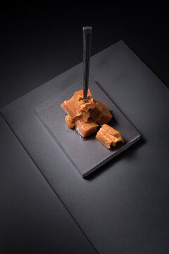 Gourmet quince jelly paste in ceramic plate on black background