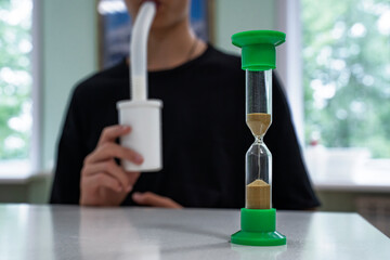 Teenager in the doctor's office doing breathing procedures tracking the time with an hourglass