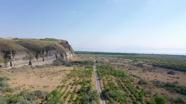 Aerial footage road between field with dry grass and small trees. Aerial view road near sand mine.   It's located near Sevan Lake, Armenia. 