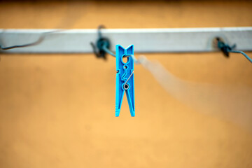 Blue clothespin isolated on yellow background 