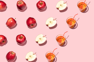 Red apples and juice on pink background. Pattern, top view, flat lay.