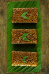Wajik on wood background. Wajik is traditional snack made with steamed glutinous (sticky) rice and further cooked in palm sugar, coconut milk, and pandan leaves.