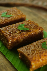 Wajik on wood background. Wajik is traditional snack made with steamed glutinous (sticky) rice and further cooked in palm sugar, coconut milk, and pandan leaves.