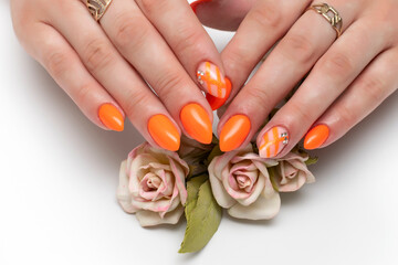 Bright orange neon manicure with stripes and crystals on a close-up of long sharp nails on a white...
