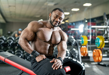 Fototapeta na wymiar Muscular shirtless bodybuilder posing for camera. Strong athlete man with naked torso in gym.
