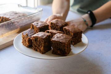 hand of a girl offering a plate with brownie pieces