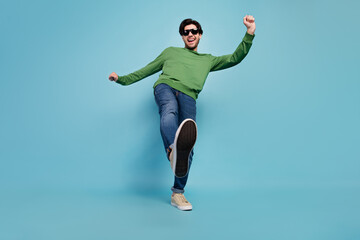 Full size photo of young good looking male in sunglass dancing discotheque raise leg isolated on blue color background