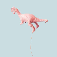 Pink dinosaur balloon on bright blue background. Minimal pastel creative idea of flying.