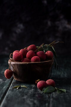 Litchi is placed in a wooden plate, peeled or unopened, on a dark wood grain table