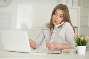  young business woman   with laptop talking on phone