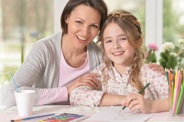 Beautiful mother and daughter drawing with her little girl