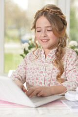 cute little girl using laptop at home