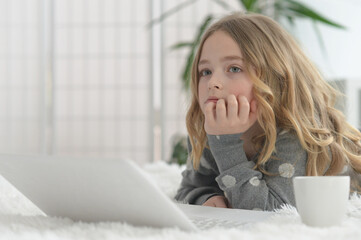 cute little girl using laptop at home on floor