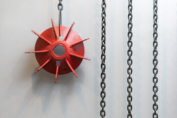 Red metallic impeller and chains hanging in loft style office as wall decoration