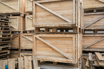 A stack of huge wooden crates in a storage area. Big boxes of goods in an open-air warehouse awaiting transportation. Logistics and distribution concept