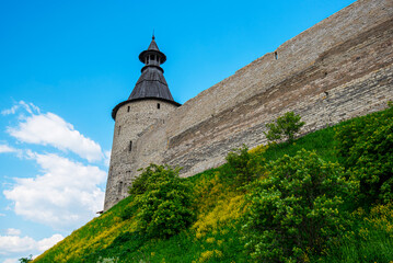 The fortress wall of a medieval fortification with towers against a bright blue sky. © eskstock
