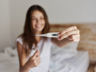 woman shows a positive temperature result on the thermometer