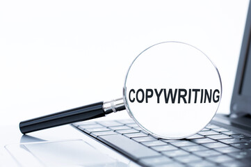 Copywriting word on a magnifier that lies on a laptop, business concept
