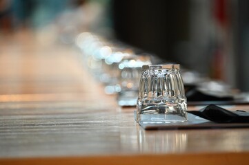 Close up view of wide social table clean place setting for dinner selective focus on a single glass