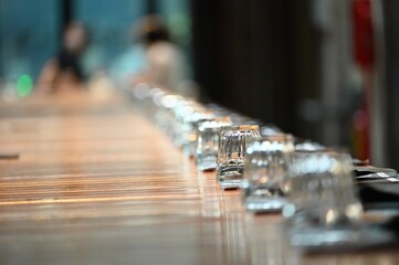 Close up view of wide social table clean place setting for dinner selective focus on a single glass