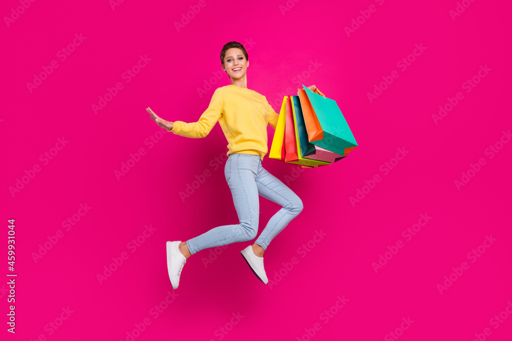 Poster Full length body size view of attractive cheerful girl jumping holding new things isolated over bright pink color background