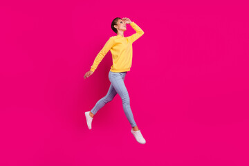 Fototapeta na wymiar Photo of cute adorable young woman dressed yellow pullover jumping looking far away empty space isolated pink color background