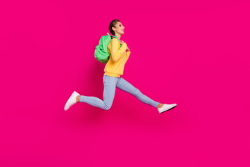 Photo of shiny charming young lady wear yellow jumper rucksack jumping running looking empty space isolated pink color background