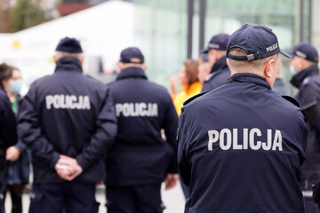 Polscy policjanci w niebieskim mundurze na zabezpieczeniu imprezy w mieście. - obrazy, fototapety, plakaty