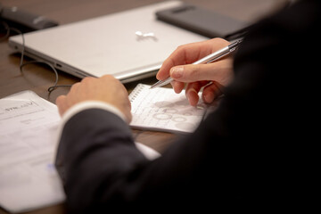 One of politician sitting by table with his hands over document during political summit or conference