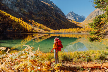 Hiker traveller woman and crystal lake in autumnal mountains.