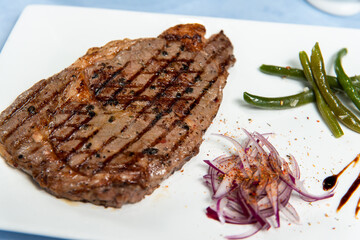 beef steak on a square white plate on a blue sky background close up