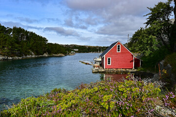 Beautiful red wooden hut on the shore of a fjord in the Nordic sea of Norway, near Bergen