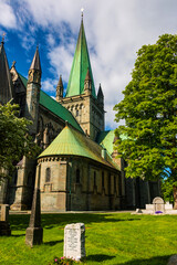 Fototapeta na wymiar Nidaros Cathedral, (Nidarosdomen) Trondheim Norway framed by green trees with blue sky background